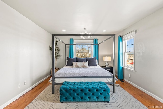 bedroom with multiple windows, wood finished floors, and baseboards