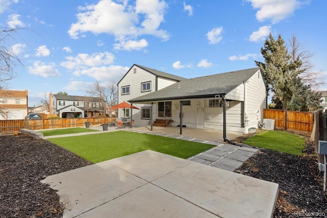 rear view of house with entry steps, a patio, a fenced backyard, a yard, and roof with shingles