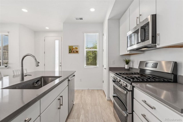 kitchen featuring recessed lighting, visible vents, a sink, white cabinetry, and appliances with stainless steel finishes