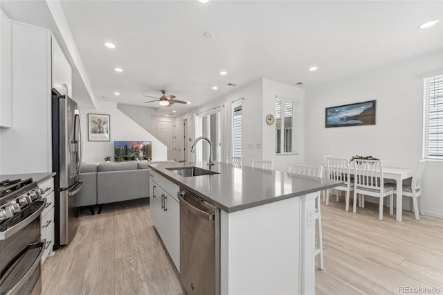 kitchen featuring a sink, stainless steel appliances, recessed lighting, open floor plan, and light wood-style floors
