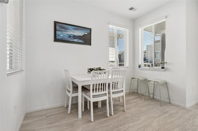 dining space with wood finished floors, visible vents, and baseboards