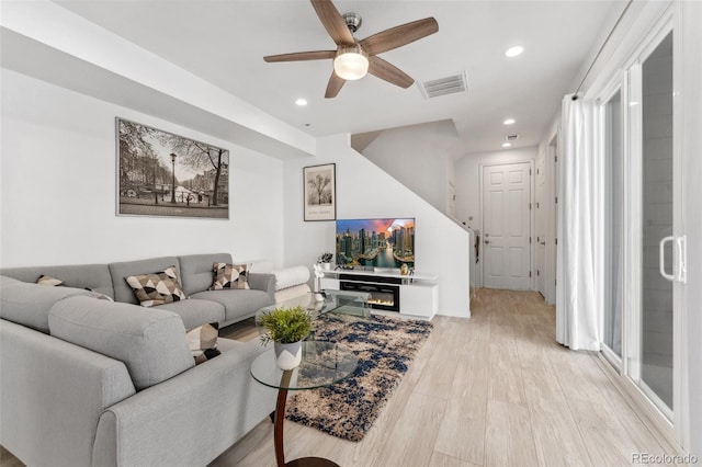 living room featuring light wood-style flooring, a ceiling fan, visible vents, and recessed lighting