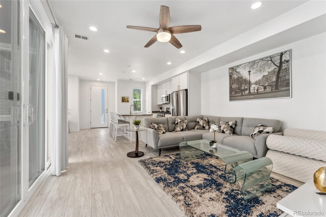 living room with light wood-style floors, visible vents, a ceiling fan, and recessed lighting