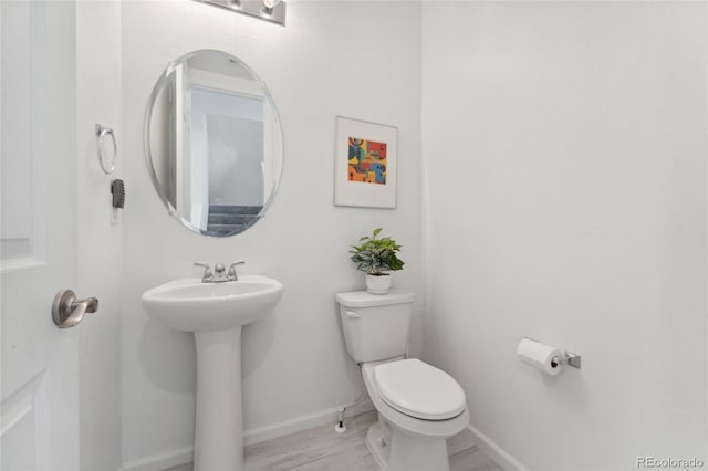 bathroom with a sink, toilet, and baseboards