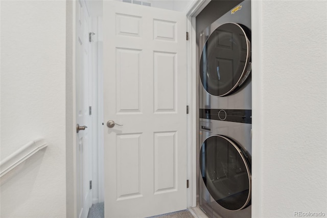 clothes washing area with stacked washing maching and dryer and laundry area
