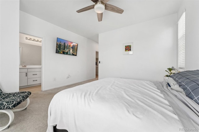 bedroom featuring light colored carpet, ensuite bathroom, a ceiling fan, and baseboards