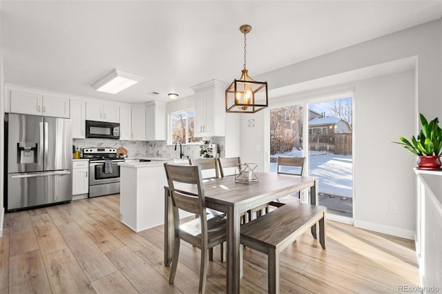 dining room featuring a notable chandelier, light hardwood / wood-style floors, and sink