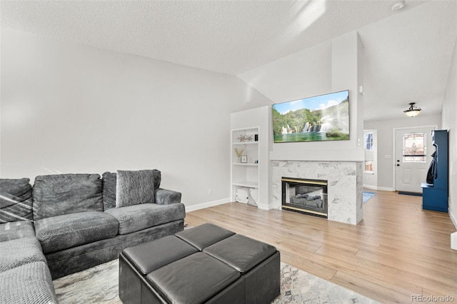 living room with a fireplace, a textured ceiling, hardwood / wood-style flooring, and built in features