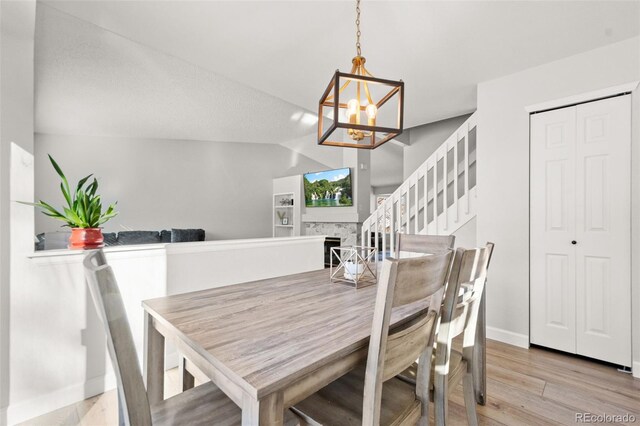 dining space featuring vaulted ceiling, light wood-type flooring, and a chandelier