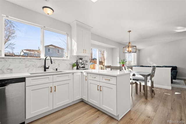 kitchen with dishwasher, white cabinets, hanging light fixtures, and sink