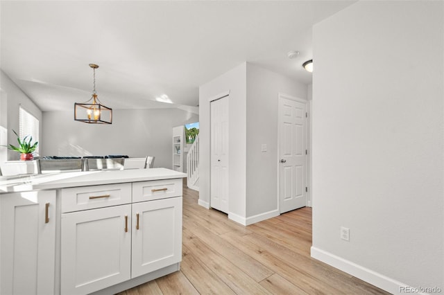 kitchen with pendant lighting, light hardwood / wood-style floors, and white cabinetry