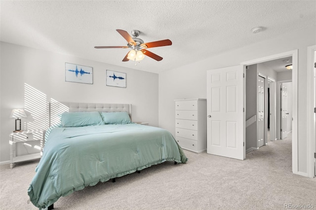 carpeted bedroom featuring ceiling fan and a textured ceiling