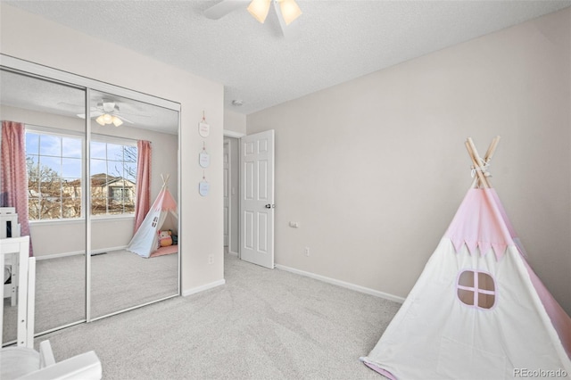 interior space featuring light carpet, a textured ceiling, a closet, and ceiling fan