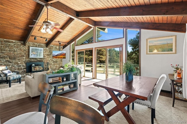 interior space with lofted ceiling with beams, a wood stove, wood ceiling, hardwood / wood-style floors, and ceiling fan