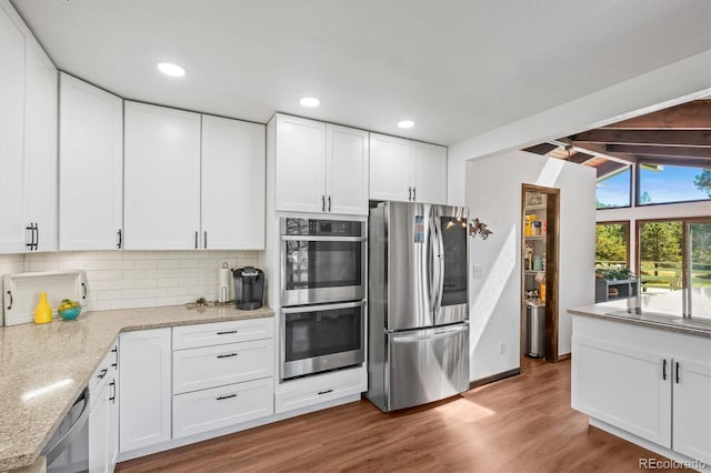 kitchen with white cabinetry, appliances with stainless steel finishes, and hardwood / wood-style flooring