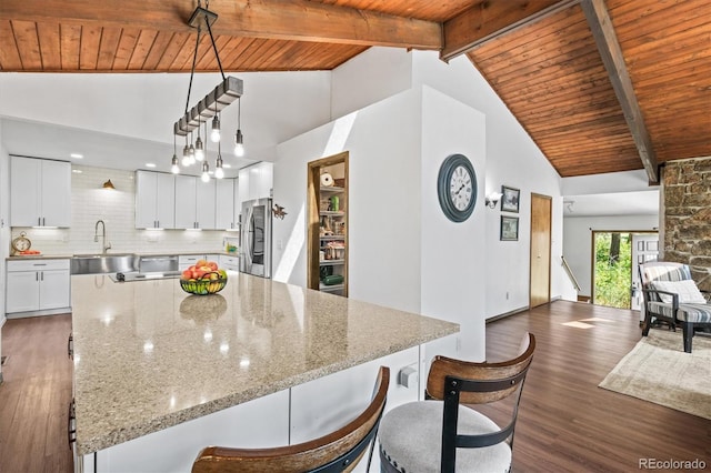 kitchen with white cabinetry, stainless steel refrigerator, dark hardwood / wood-style floors, and beam ceiling