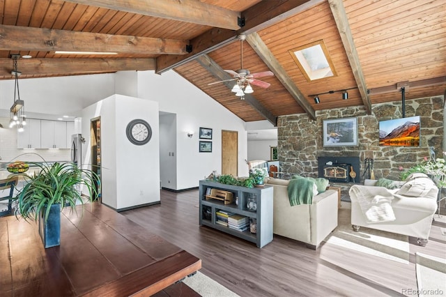 living room featuring dark wood-type flooring, wooden ceiling, high vaulted ceiling, a skylight, and beam ceiling