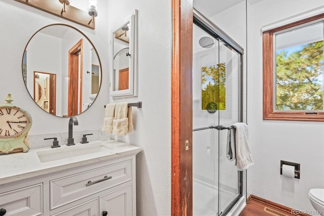 bathroom with a shower with shower door, vanity, toilet, and wood-type flooring