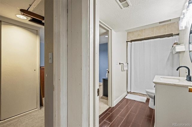 bathroom with toilet, curtained shower, a textured ceiling, hardwood / wood-style flooring, and vanity