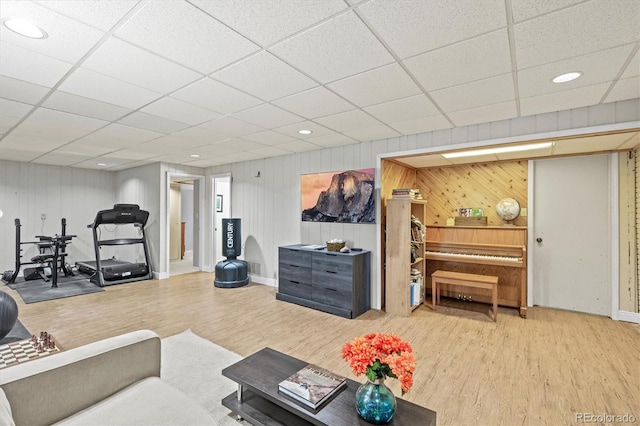 living room featuring wood walls, hardwood / wood-style flooring, and a paneled ceiling