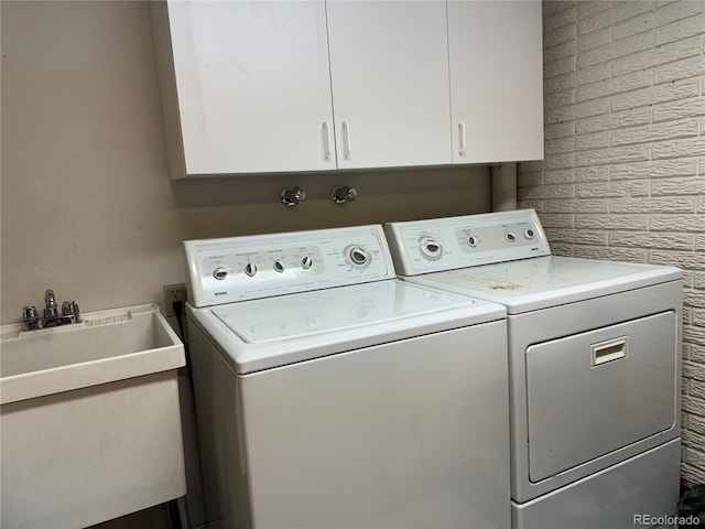 laundry area with washing machine and clothes dryer, cabinets, and sink