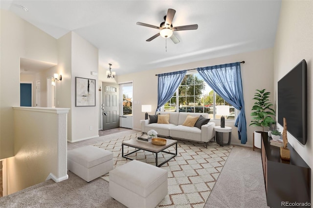 carpeted living room with ceiling fan with notable chandelier and vaulted ceiling