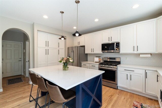 7853 S Jasper Way, Englewood, CO 80112 - kitchen featuring stainless steel appliances, arched walkways, white cabinetry, a center island, and recessed lighting