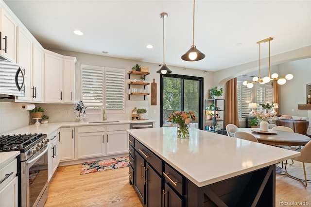 7853 S Jasper Way, Englewood, CO 80112 - kitchen featuring stainless steel gas range oven, white cabinets, arched walkways, light countertops, and light wood-style floors