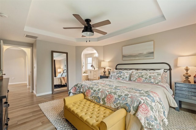 7853 S Jasper Way, Englewood, CO 80112 - bedroom with arched walkways, a tray ceiling, wood finished floors, ensuite bathroom, and a ceiling fan