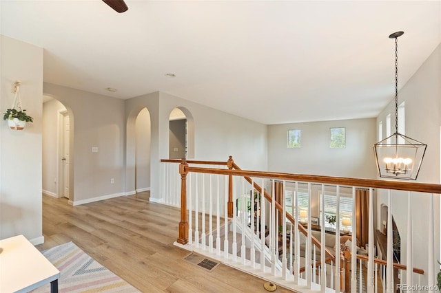 7853 S Jasper Way, Englewood, CO 80112 - corridor with an upstairs landing, light wood-style flooring, a chandelier, and arched walkways
