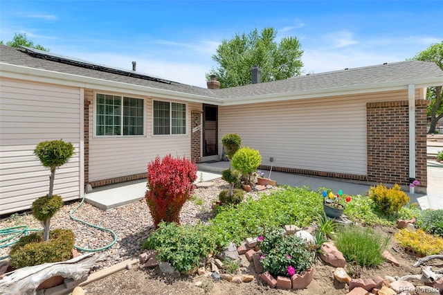 7260 Otis Ct, Arvada, CO 80003 - view of front of home with solar panels, brick siding, roof with shingles, and a chimney