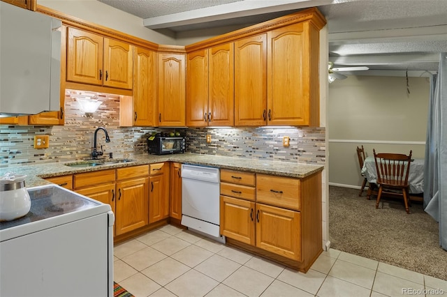 7260 Otis Ct, Arvada, CO 80003 - kitchen with white dishwasher, range, ceiling fan, light tile patterned floors, and light stone countertops