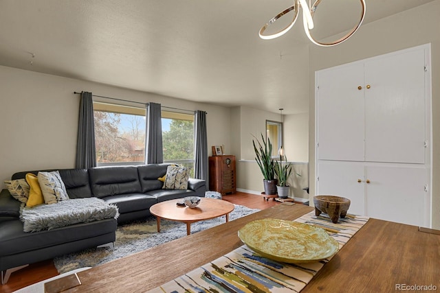 living room with a chandelier, baseboards, and wood finished floors