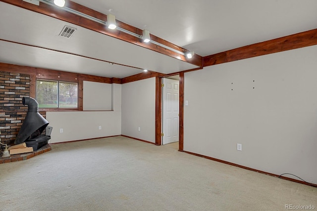below grade area with a wood stove, carpet, visible vents, and baseboards