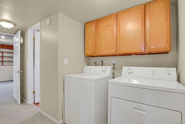 clothes washing area featuring baseboards, light carpet, washer and dryer, and cabinet space