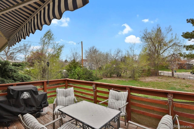 wooden terrace with a lawn and outdoor dining area