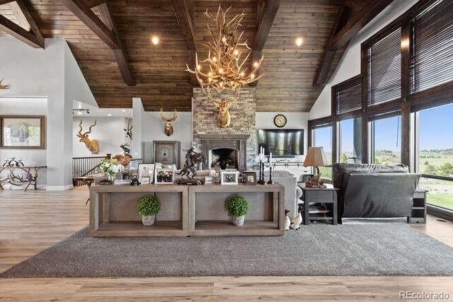 15295 E Cherry Creek S Road, Larkspur, CO 80118 - living area featuring wood ceiling with exposed beams, high vaulted ceiling, wood finished floors, baseboards, and a chandelier