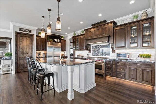 15295 E Cherry Creek S Road, Larkspur, CO 80118 - kitchen with premium appliances, ornamental molding, decorative backsplash, glass insert cabinets, and dark stone counters