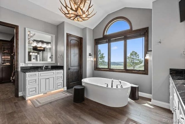 15295 E Cherry Creek S Road, Larkspur, CO 80118 - bathroom featuring vanity, wood finished floors, a freestanding tub, a chandelier, and lofted ceiling