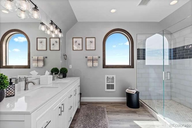 15295 E Cherry Creek S Road, Larkspur, CO 80118 - full bathroom with heating unit, double vanity, wood finished floors, a shower stall, and baseboards