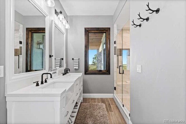 15295 E Cherry Creek S Road, Larkspur, CO 80118 - full bathroom with wood finished floors, double vanity, baseboards, and a stall shower