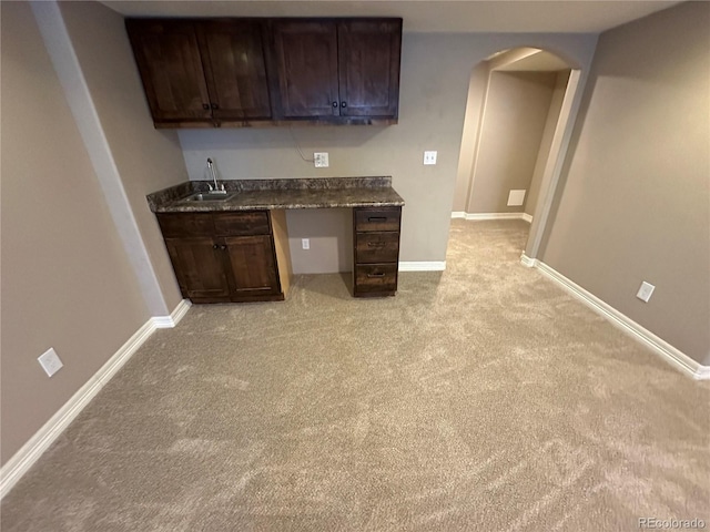4746 Raven Run, Broomfield, CO 80023 - kitchen with light colored carpet, baseboards, a sink, dark countertops, and arched walkways