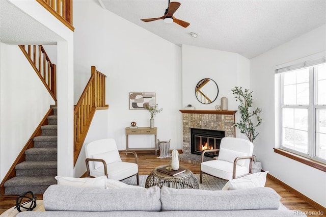 2040 S Xenia Way, Denver, CO 80231 - living area featuring stairway, wood finished floors, ceiling fan, a brick fireplace, and high vaulted ceiling