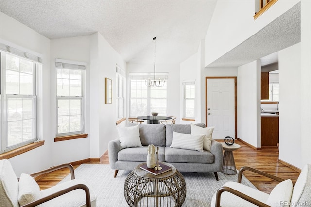 2040 S Xenia Way, Denver, CO 80231 - living area featuring a chandelier, healthy amount of natural light, wood finished floors, lofted ceiling, and a textured ceiling