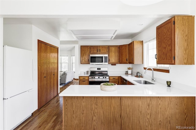 2040 S Xenia Way, Denver, CO 80231 - kitchen featuring appliances with stainless steel finishes, a peninsula, brown cabinets, and healthy amount of natural light