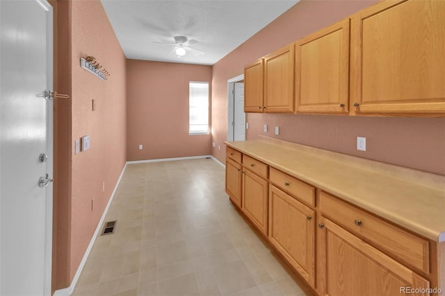 kitchen with ceiling fan and light brown cabinetry