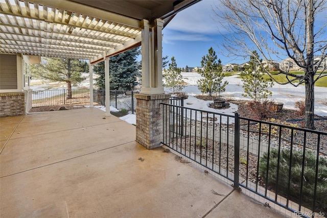 snow covered patio featuring a pergola and a fire pit