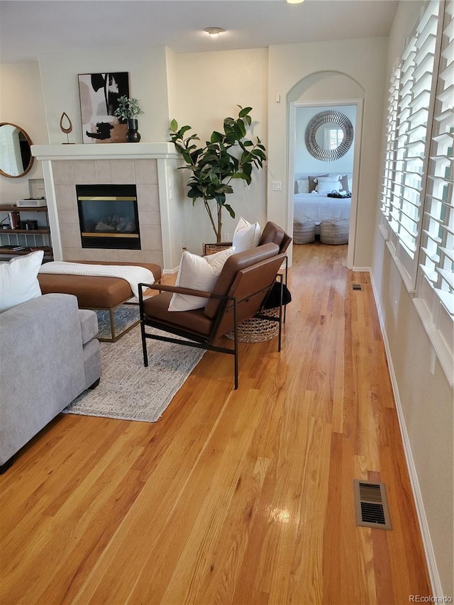 living room with a tiled fireplace and light hardwood / wood-style floors