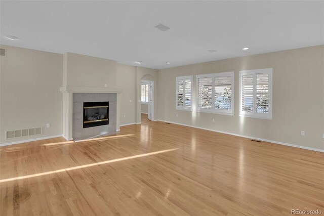 unfurnished living room featuring a tiled fireplace and light hardwood / wood-style floors