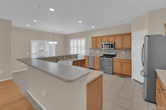 kitchen with sink, stainless steel appliances, tasteful backsplash, a center island with sink, and decorative light fixtures